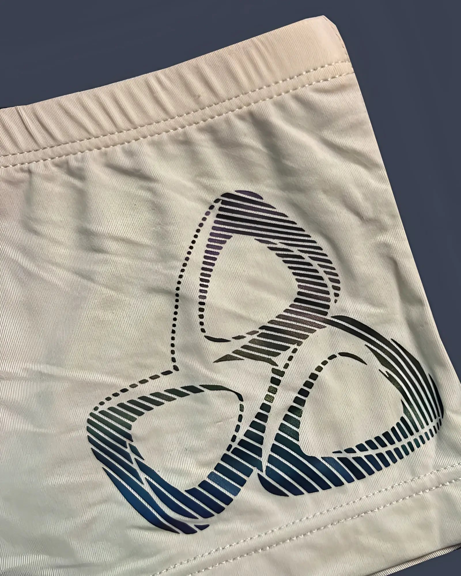 Cream-colored private structure brut4390 bare hipster shorts with bold blue and black gradient biohazard symbol