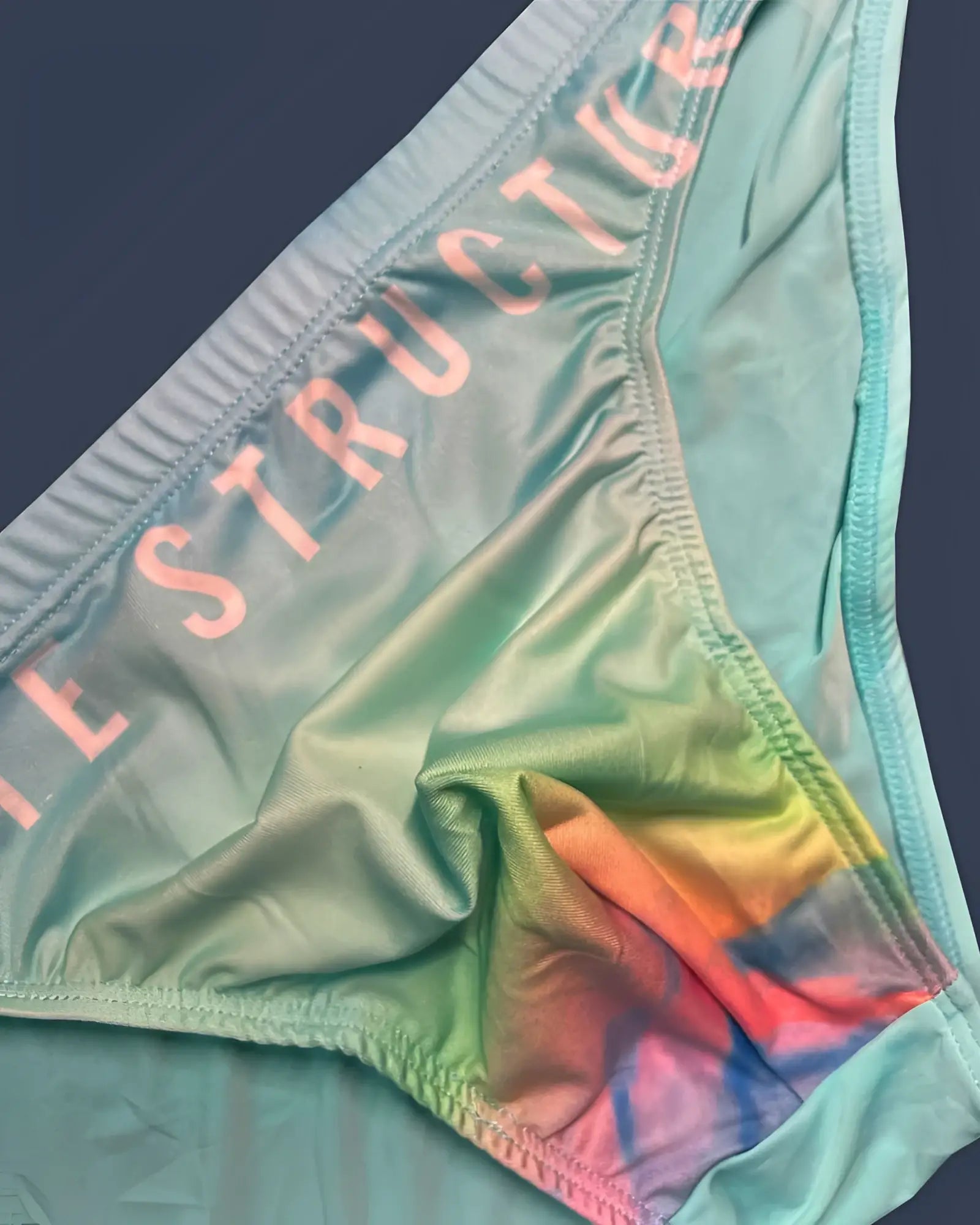 Pastel green tie-dye bikini bottom with instructor printed in pink on the waistband from private structure in cyan mist color