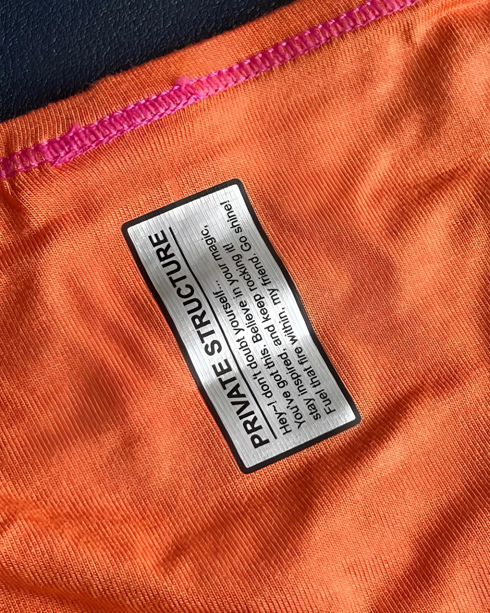 Orange private structure prime eutopia bikini brief with black and silver label stitched on fabric seam