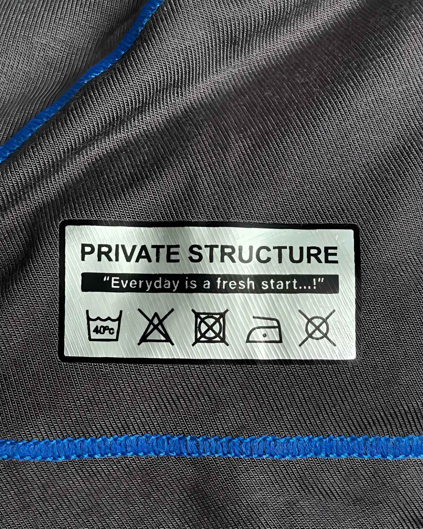 Gray fabric hipster underwear with blue stitching and private structure care label showing laundry instructions