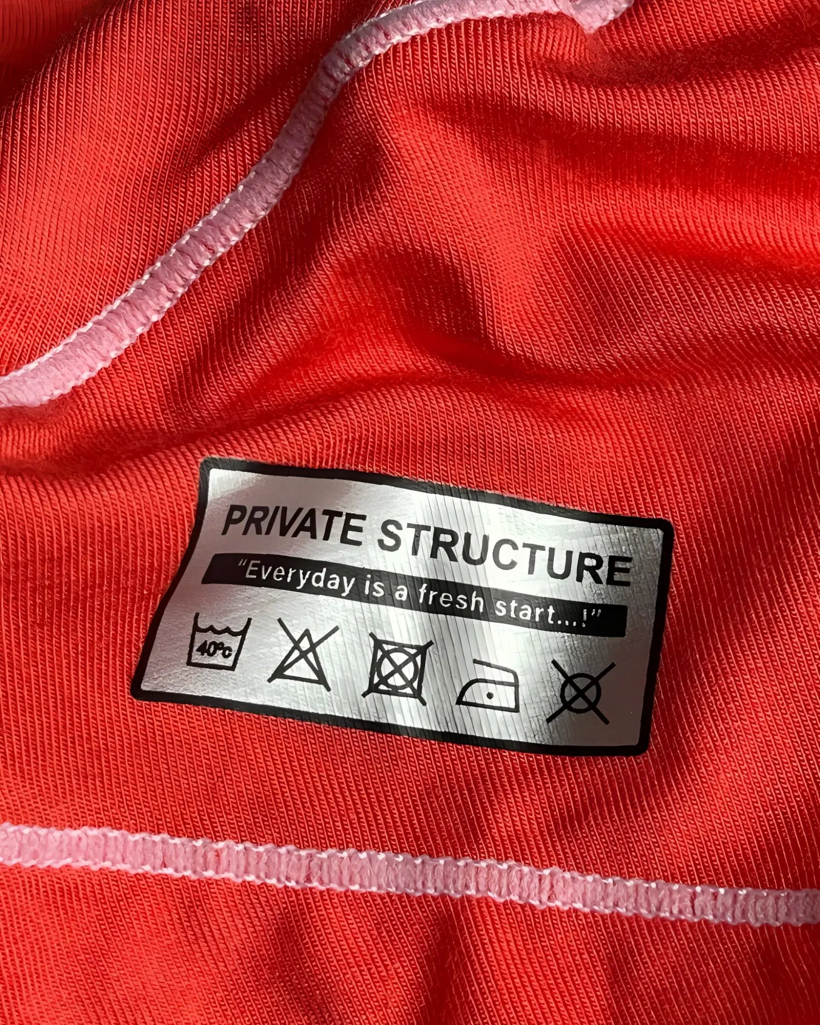 Back side of private structure epus4570 prime elysian hipster red featuring a silver care label with laundry instructions