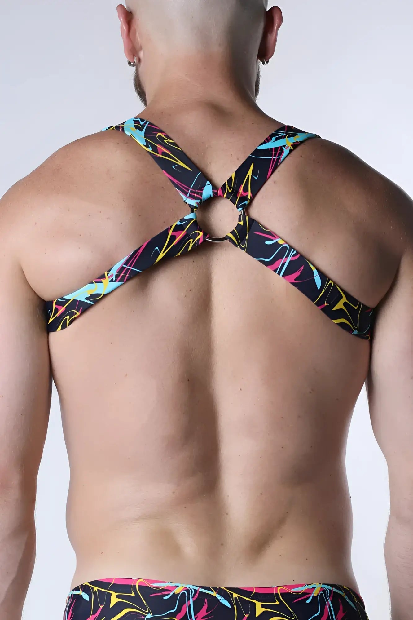 Black neon-colored abstract patterned strappy backless top with central metal ring pulse elastic harness back view
