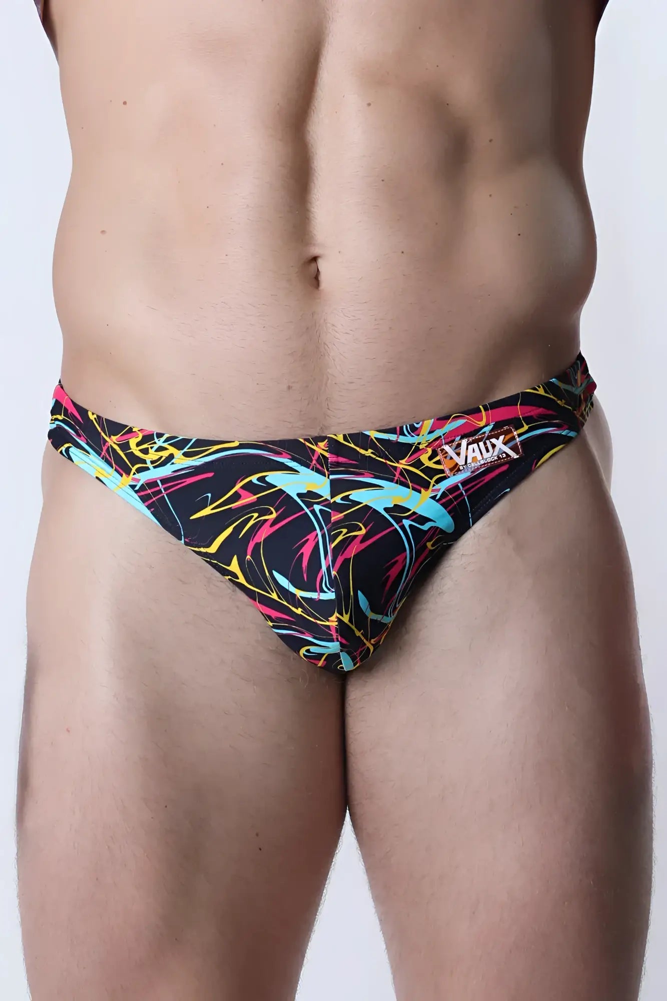 Vaux pulse swim thong featuring neon pink yellow and cyan abstract lines on black for men’s swimwear