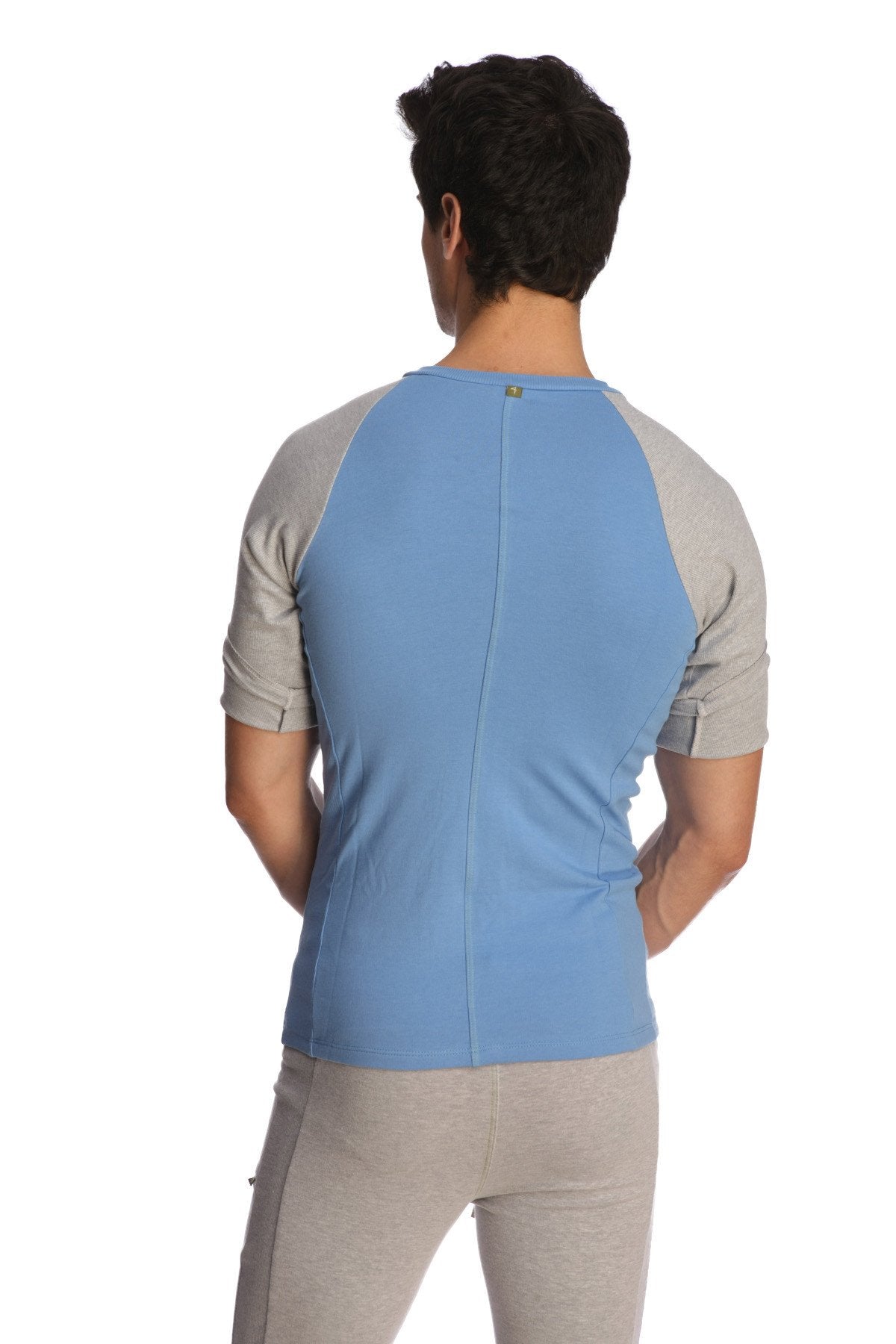 Back view of light blue and gray raglan sleeve athletic shirt with subtle vertical seam in raglan virtual crew neck style