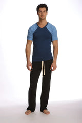 Man wearing a royal blue raglan virtual crew neck t-shirt with navy and light blue sleeves and black pants with cream drawstrings