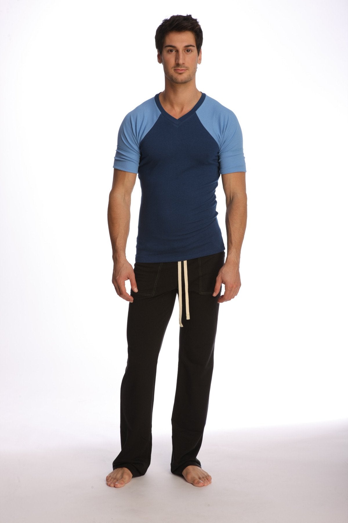Man wearing a royal blue raglan virtual crew neck t-shirt with navy and light blue sleeves and black pants with cream drawstrings