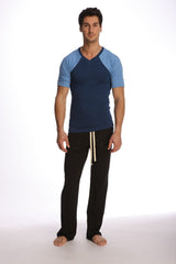 Man wearing a royal blue raglan virtual crew neck t-shirt with navy and light blue sleeves and black pants with cream drawstrings