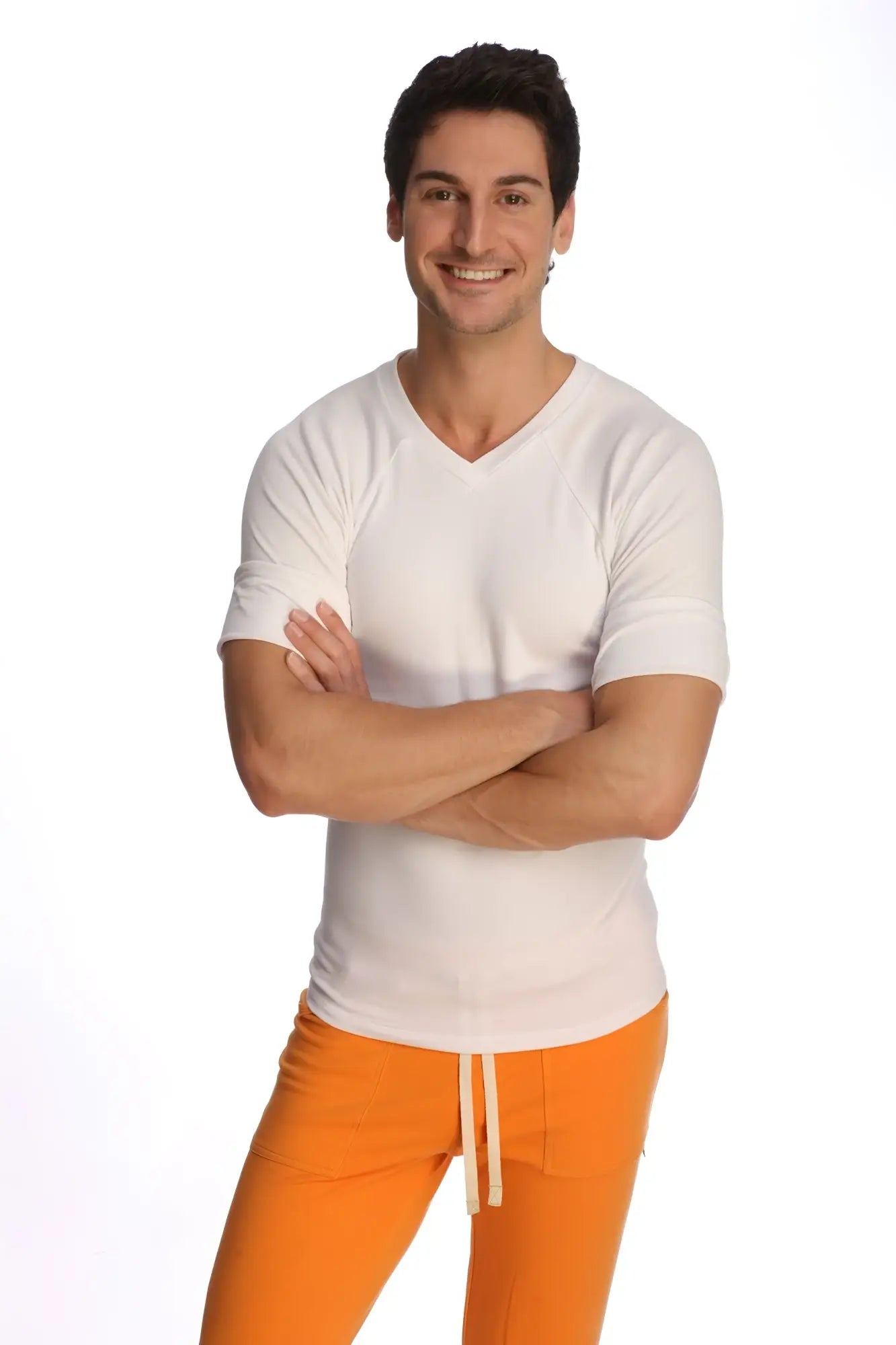 A man wearing a white raglan virtual crew neck shirt with a v-neck and bright orange drawstring pants