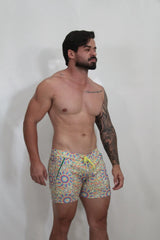 Rainbow kaleidoscope linen texture shorts featuring multicolored patterned swim trunks with bright yellow drawstring
