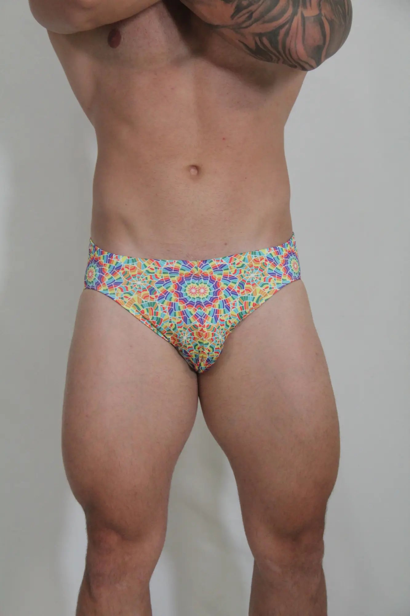 Rainbow kaleidoscope swim brief with vibrant multicolored geometric mandala pattern for stylish swimwear