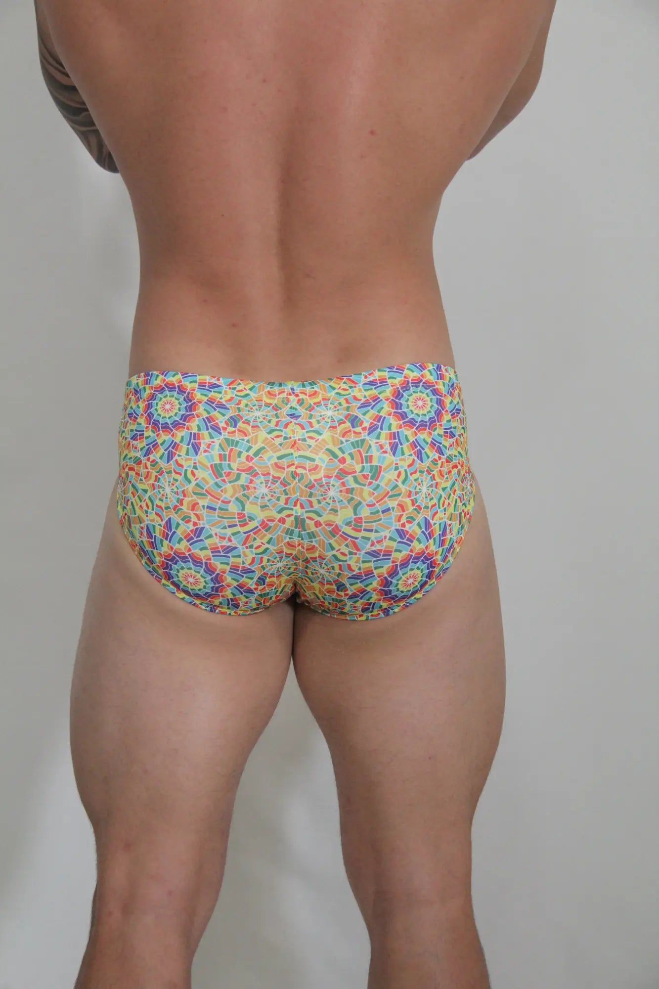 Rainbow kaleidoscope swim brief featuring vibrant multicolored mosaic pattern with bold geometric design