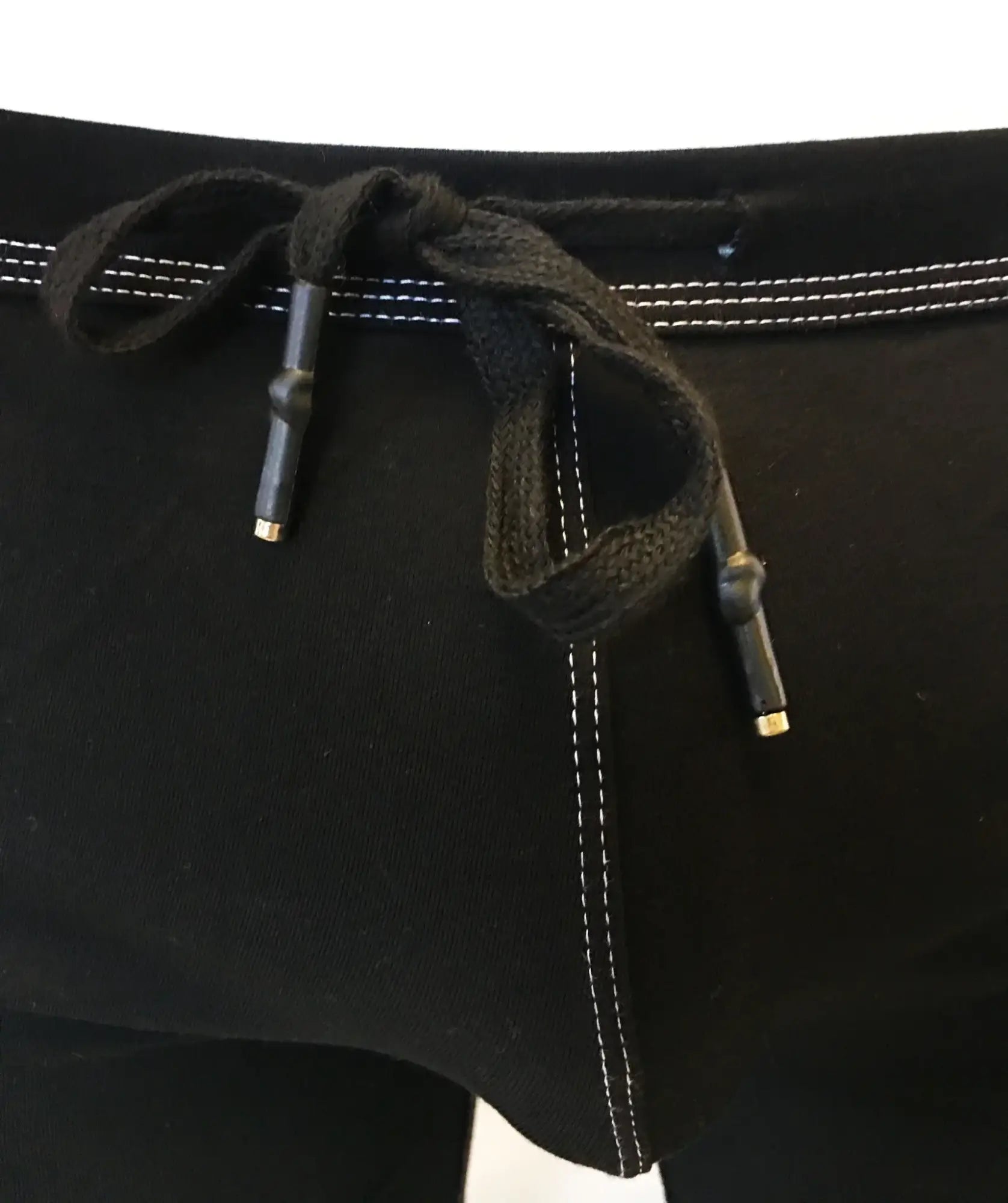 Black drawstring waistband with white stitching and metallic aglets on rainbow ribbon shorts waistband detail