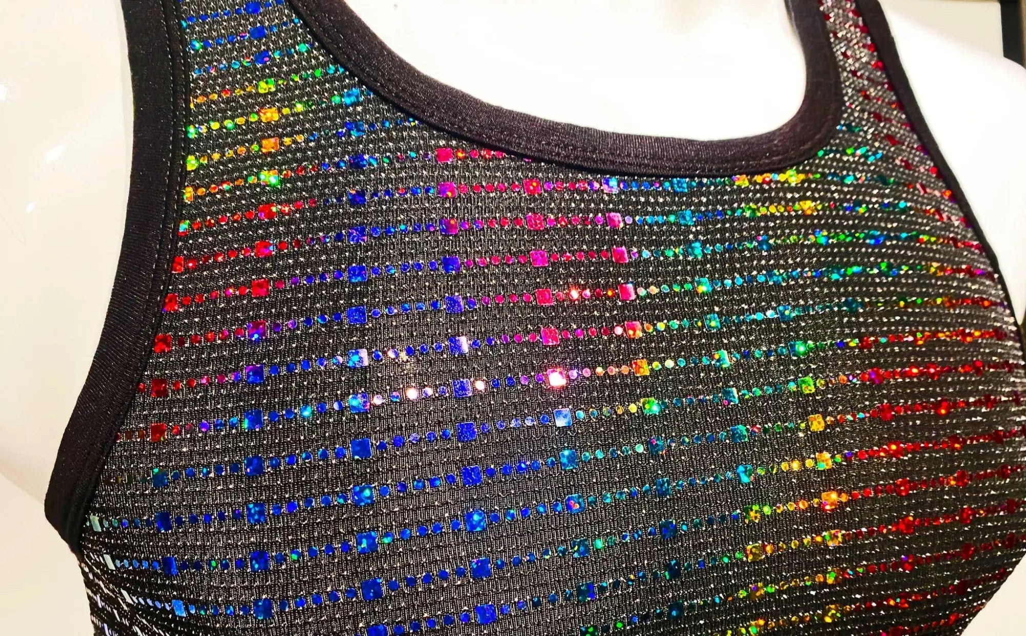 A black sequined tank top with vibrant rainbow-colored rhinestones in diagonal stripes called rainbow sequin tank