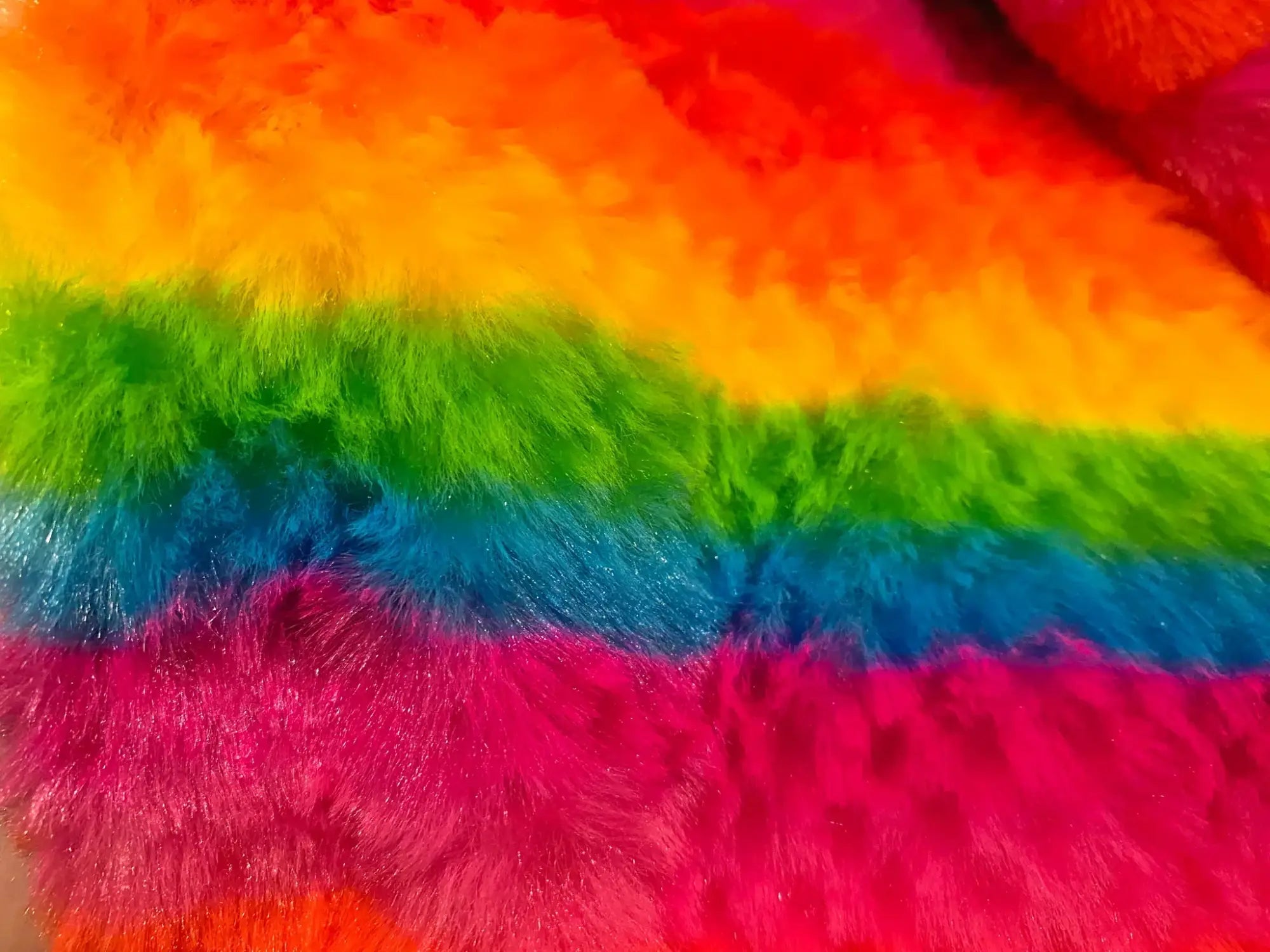 Rainbow stripe faux fur hoodie with fluffy rainbow-colored fabric featuring vibrant red orange yellow green blue and pink