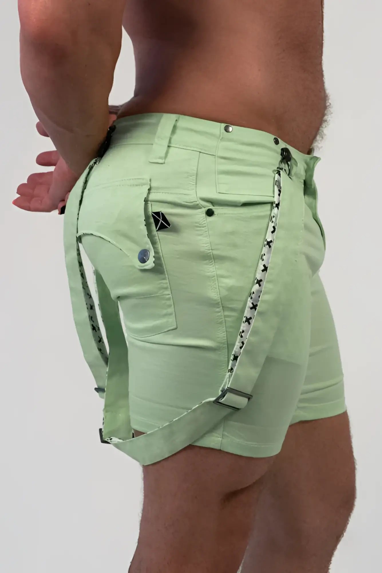 Romey shorts in light green with black star patterned straps and a small black logo on the pocket