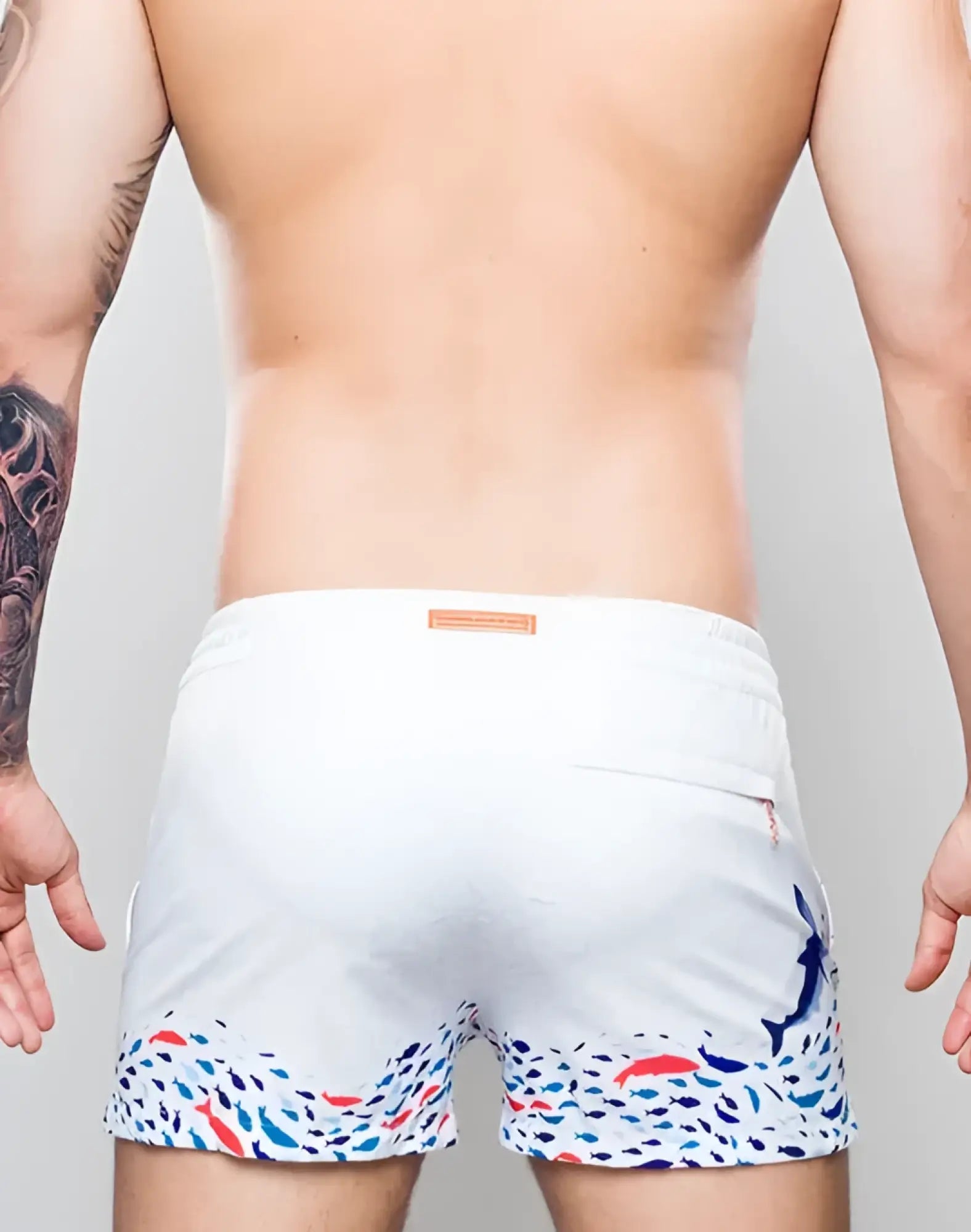 White s50 seascape print swim short with vibrant colorful fish pattern hem and subtle blue dolphin on right leg