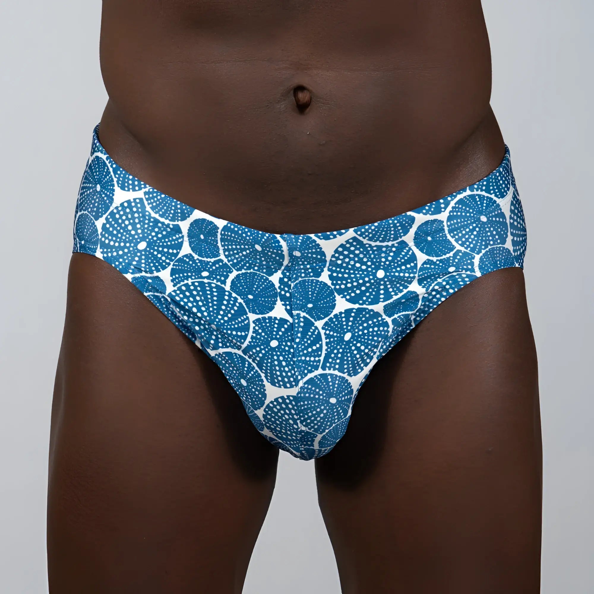 Blue and white patterned sand dollar brief swim trunks with circular dotted motifs for beach and pool use