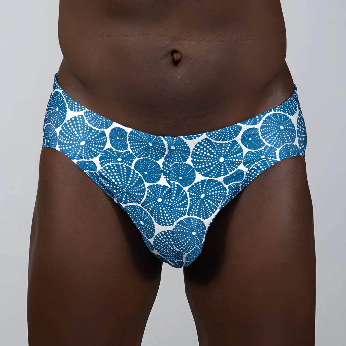 Blue and white patterned sand dollar brief swim trunks with circular dotted motifs for beach and pool use