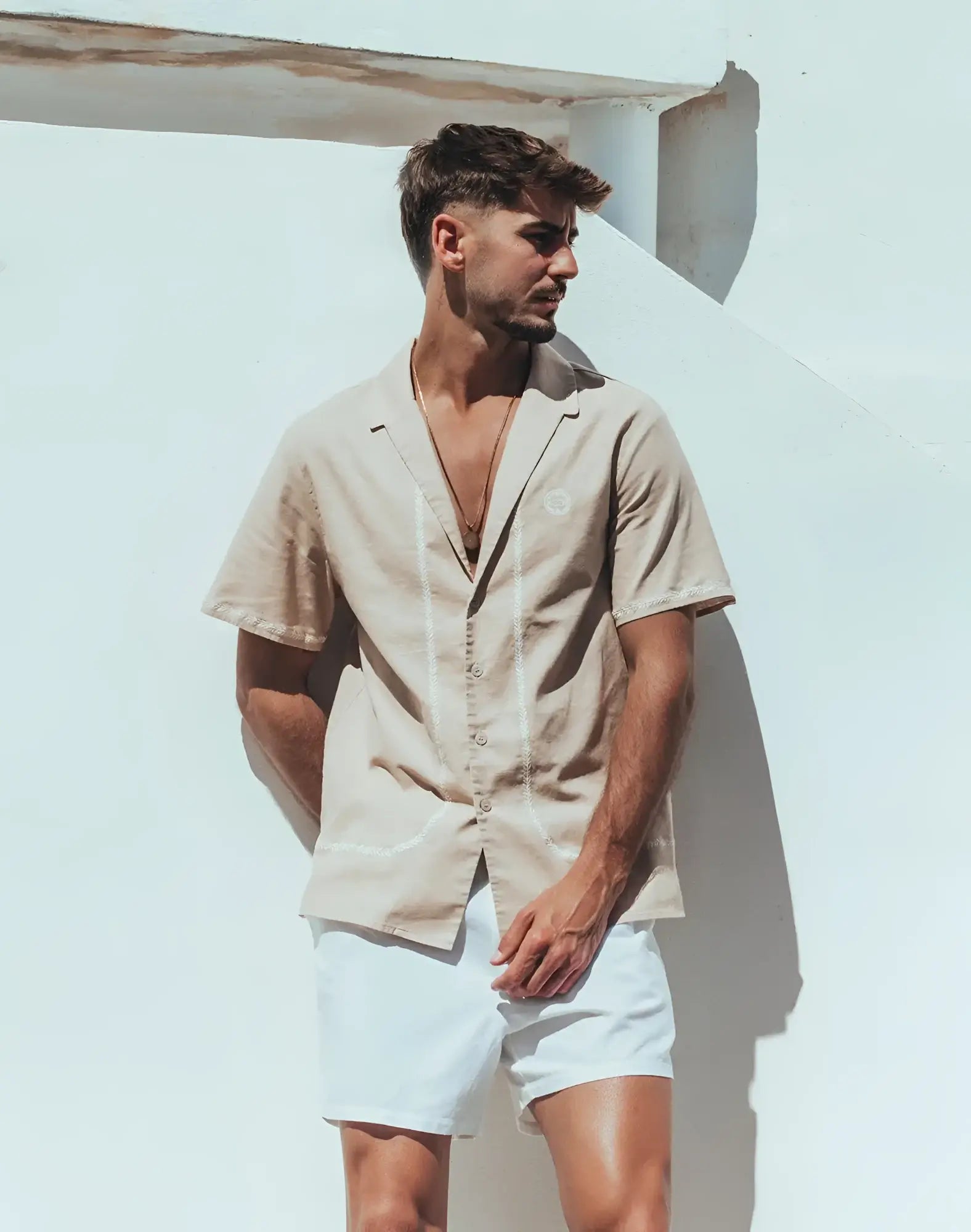 Beige santorini linen shirt with short sleeves and subtle white stitching along the placket and front seams