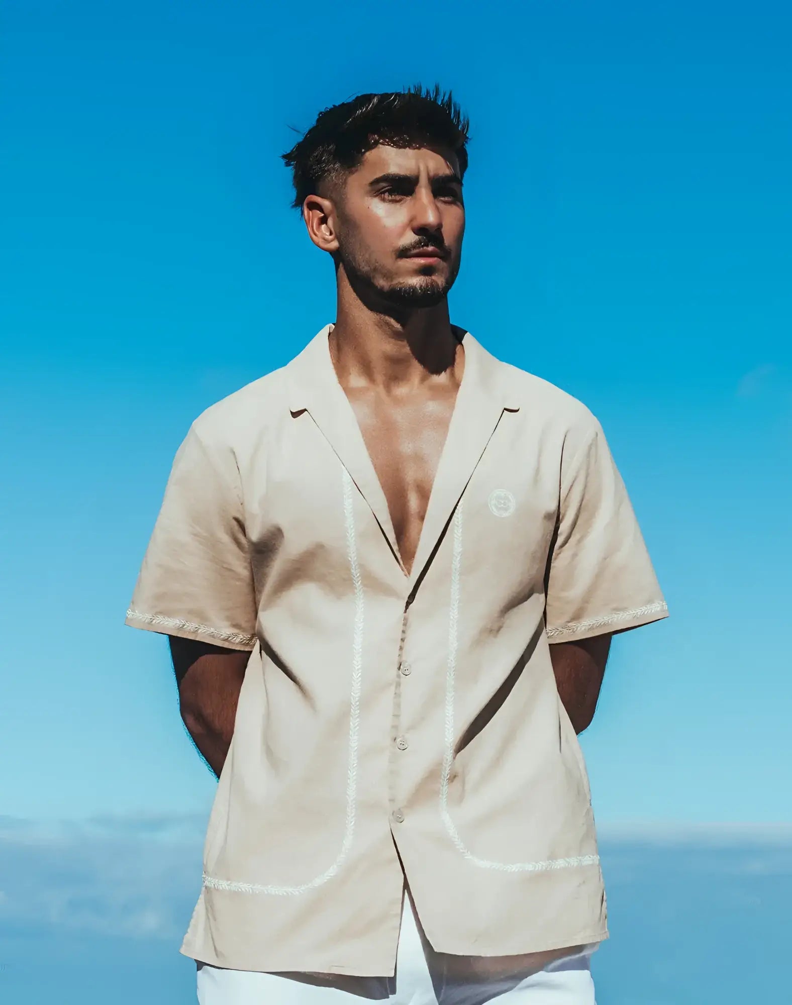 Beige santorini linen shirt with short sleeves and white stitching along the front placket and hem