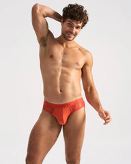 Bright orange score sheer brief with solid waistband and amm logo made of sheer mesh fabric