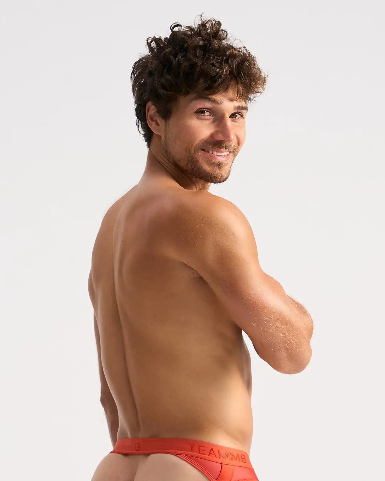 A man wearing bright red score sheer jock briefs with a visible Calvin Klein logo waistband from the front