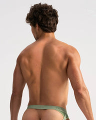 A man wearing olive green low-rise SCORE SHEER JOCK briefs with sheer material and teal waistband branding