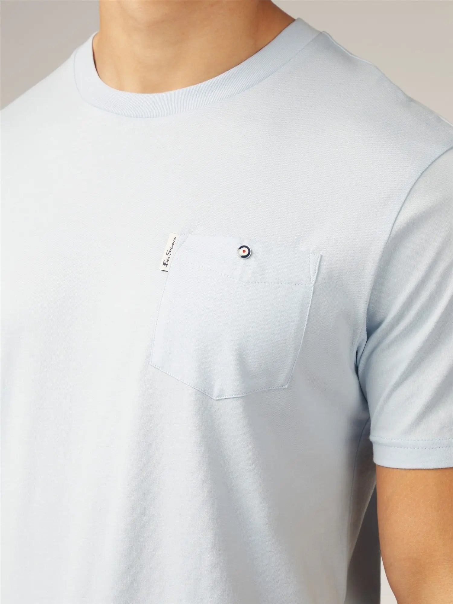Light blue signature t-shirt with short sleeves and chest pocket featuring a small black and white button closure