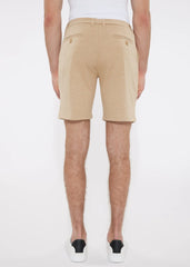 Beige solid stretch knit shorts with tailored fit and buttoned back pockets shown from the back side