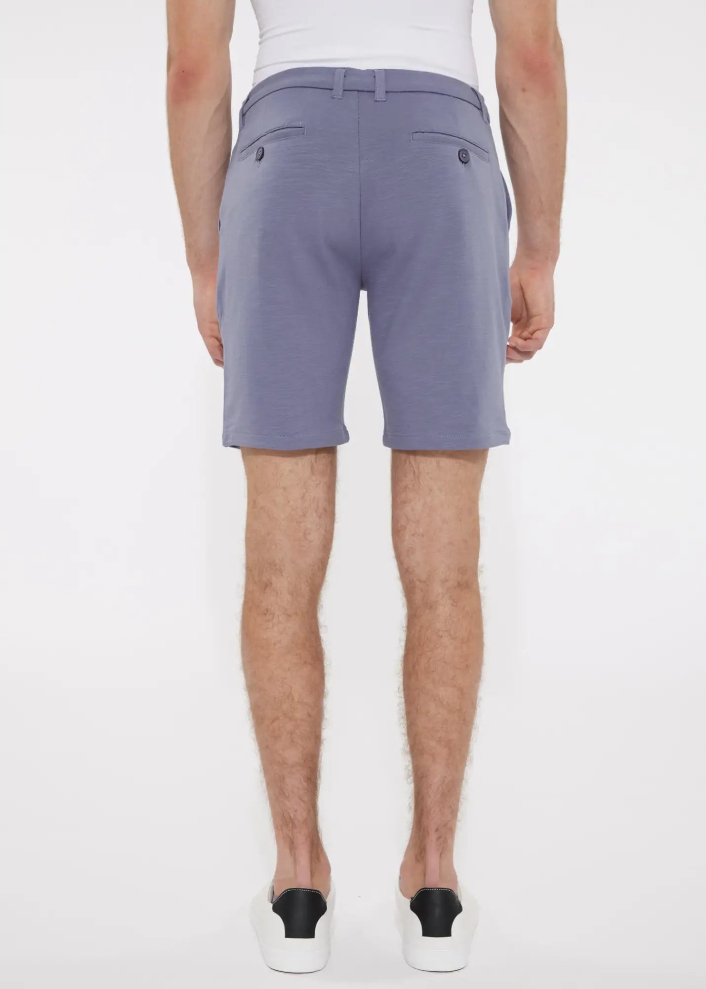 A pair of solid stretch knit shorts in soft lavender with lightweight fabric and dark button accents on back pockets backside view