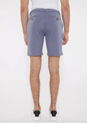 A pair of solid stretch knit shorts in soft lavender with lightweight fabric and dark button accents on back pockets backside view