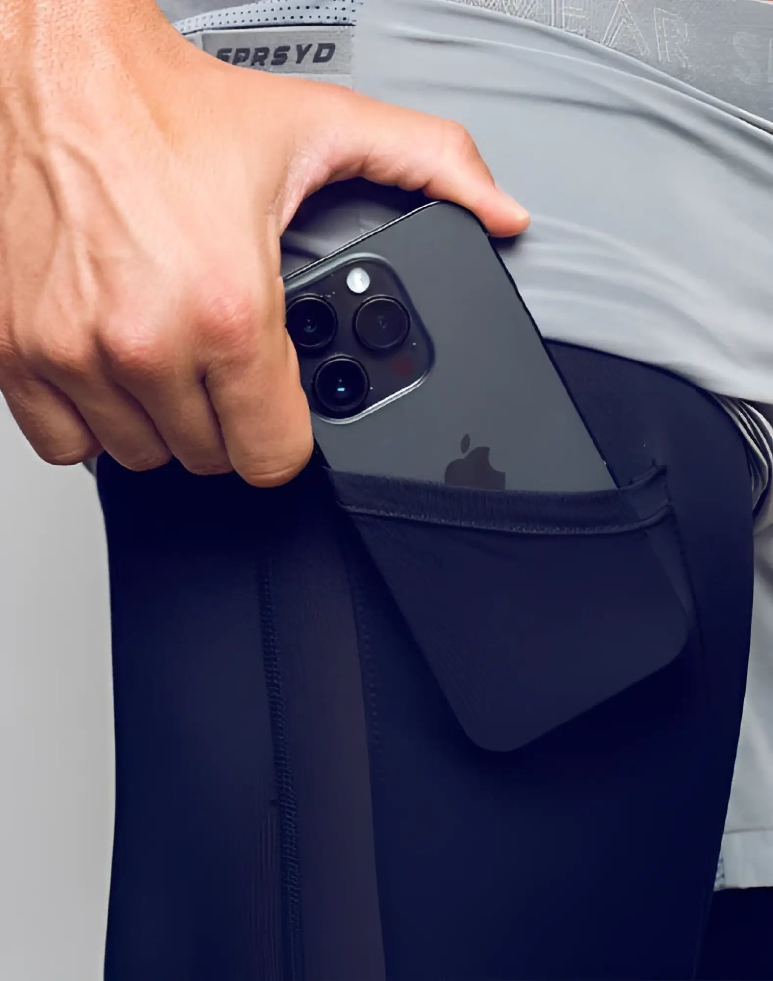 Black iphone with triple camera system in pocket of dark navy breathable spr flex short athletic leggings back view