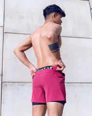 Spr max short vibrant fuchsia athletic shorts with black waistband white lettering layered over dark blue compression shorts