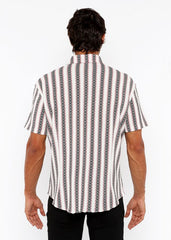 A man wearing a zigzag stripe open stretch knit shirt with white black and gray vertical chain-like patterns
