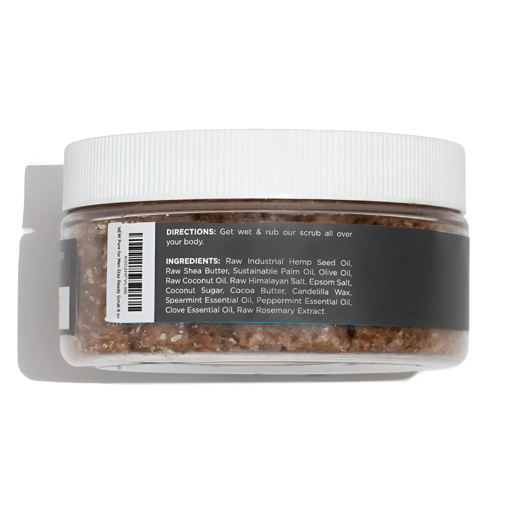 A clear plastic jar with a white lid contains brown granular stay ready scrub body scrub with label directions