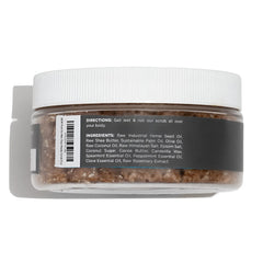 A clear plastic jar with a white lid contains brown granular stay ready scrub body scrub with label directions