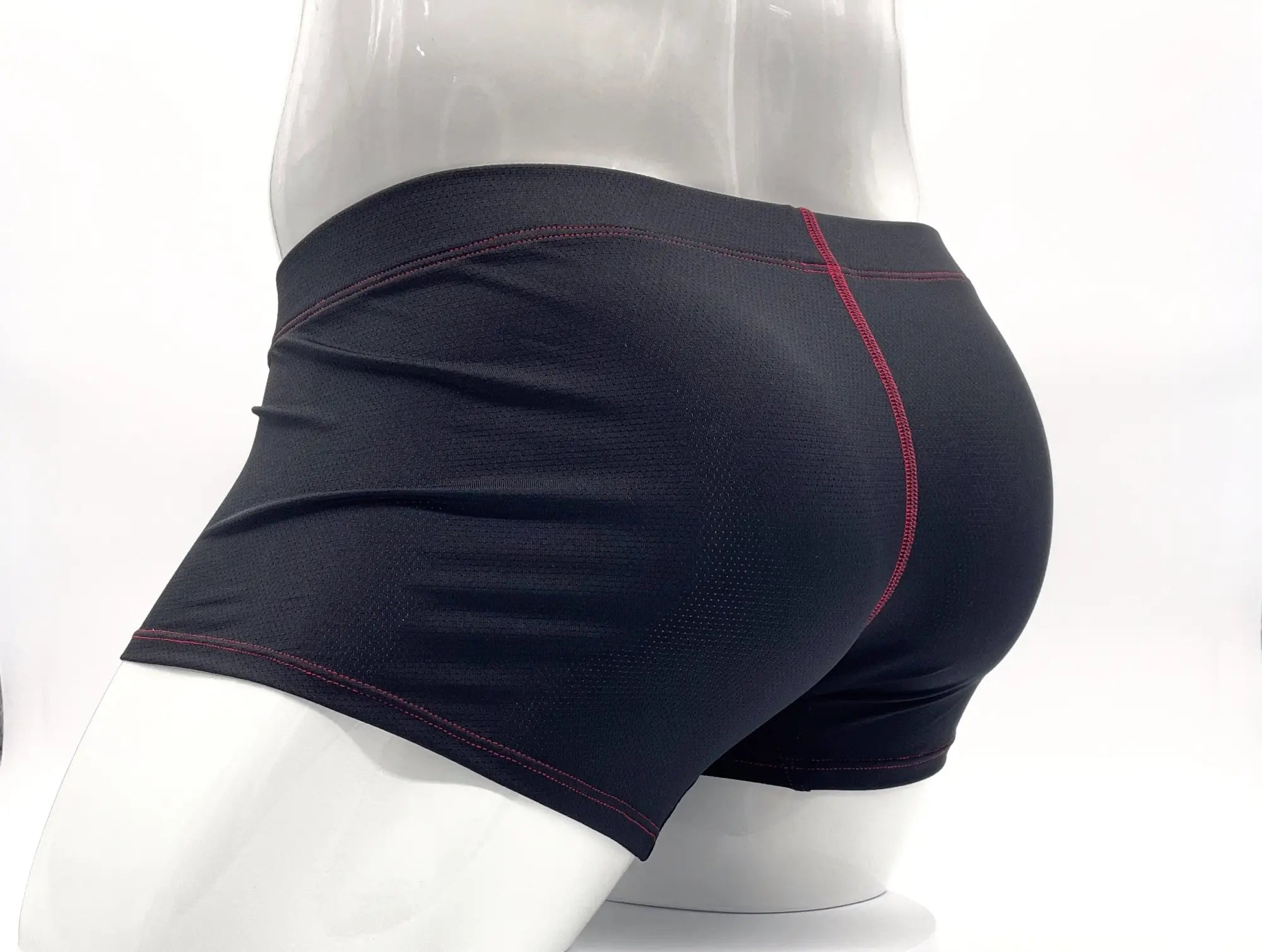Black athletic boxer briefs with red stitching along seams displayed on a mannequin for active use