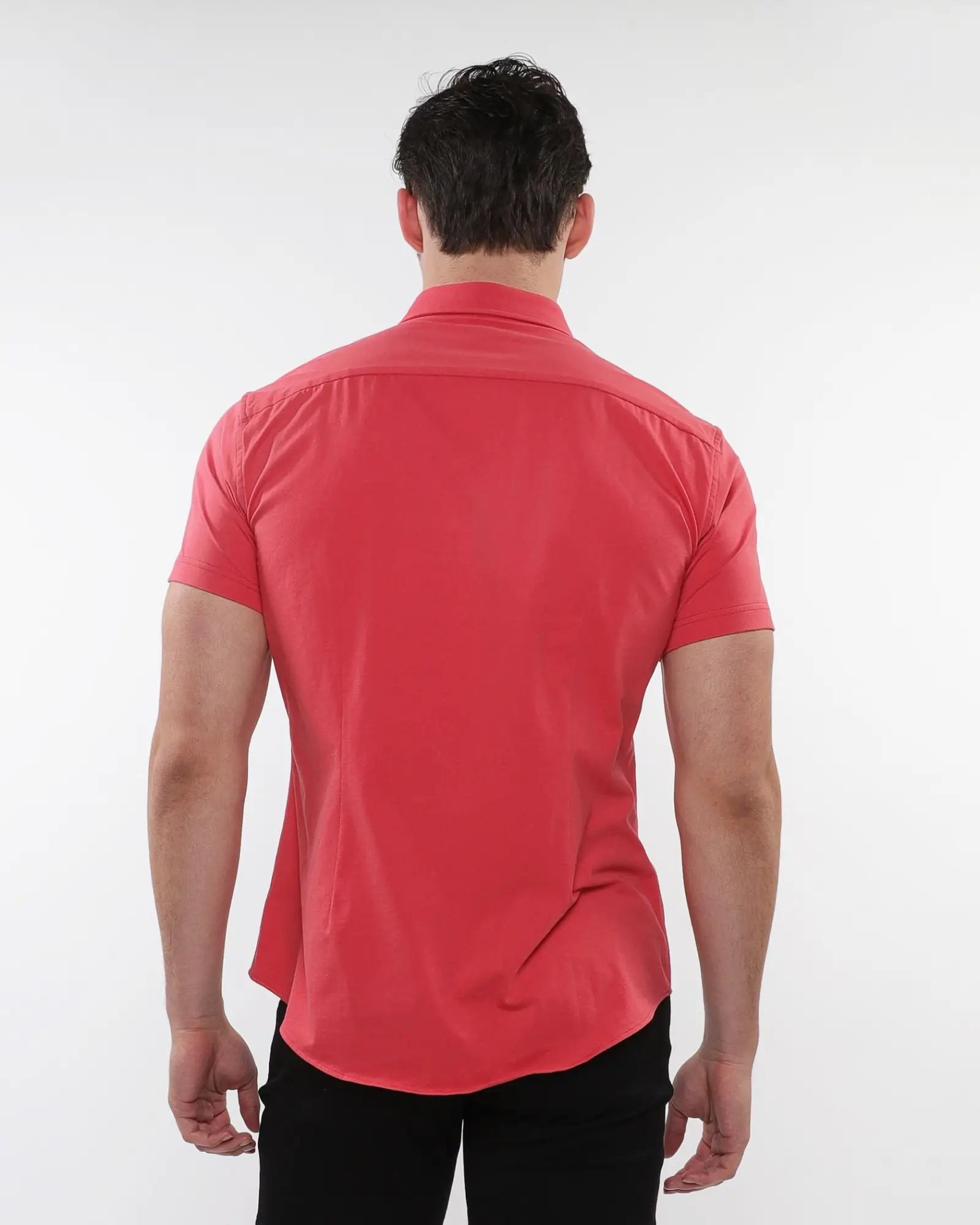 A man wearing a vibrant coral stretch knit shirt with tailored fit and subtle stitching details