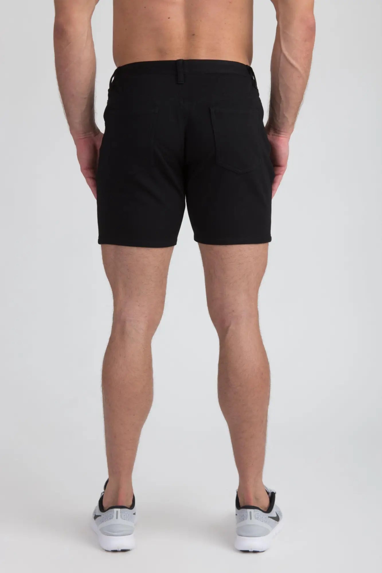 Black stretch knit shorts with tailored fit and two rear pockets shown from the back side