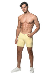 A pair of pale yellow stretch knit shorts with a single button closure and side pockets in a form-fitting design