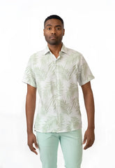 A man wearing a summer rain s s shirt with light green palm leaf pattern on off white short sleeved button up shirt