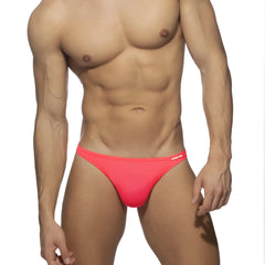 Bright pink form-fitting swimwear g-string trunks with subtle brand logo on the waistband front view