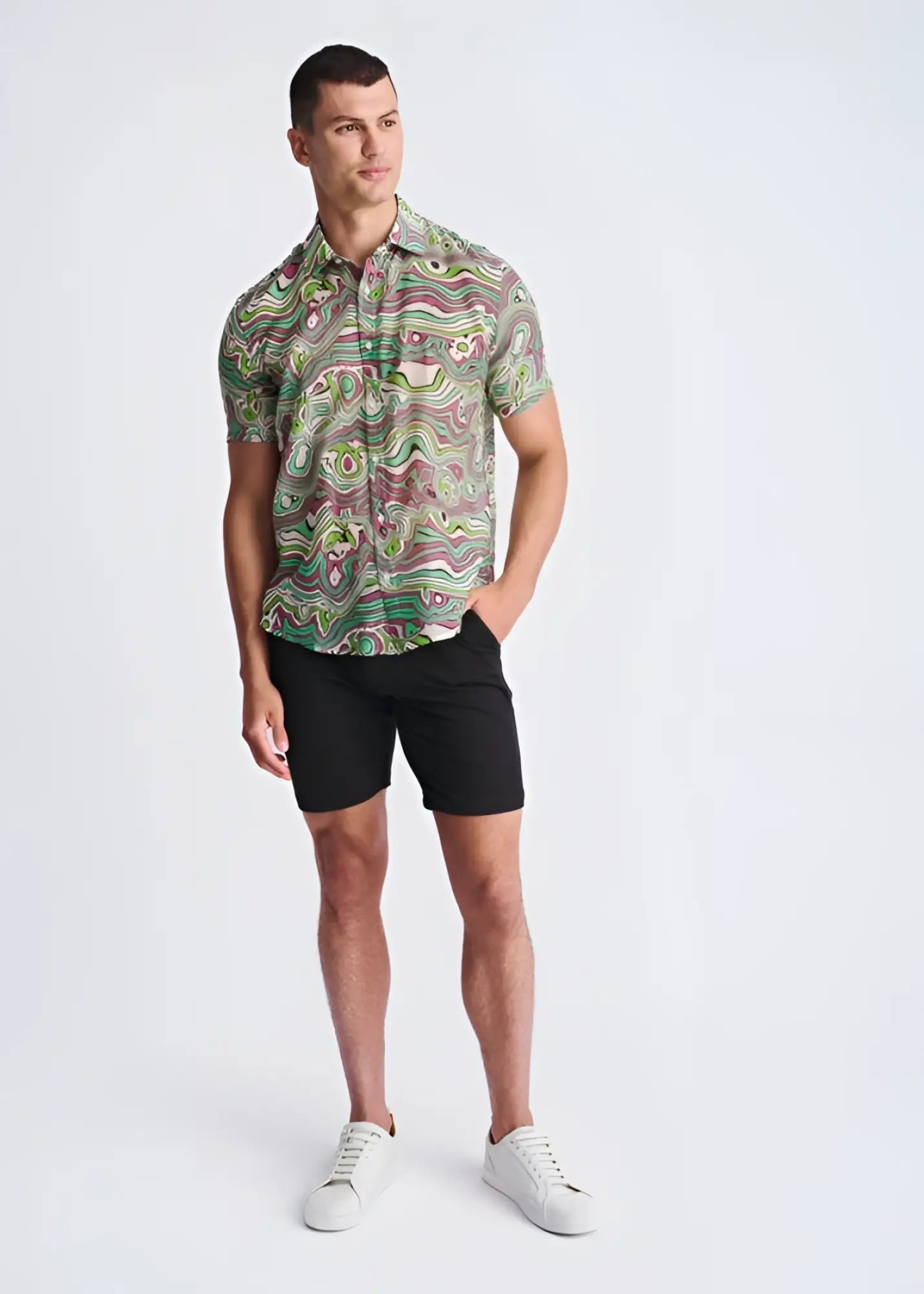 A man wearing a swirls lightweight cotton silk short-sleeved shirt with green pink and beige abstract swirl patterns