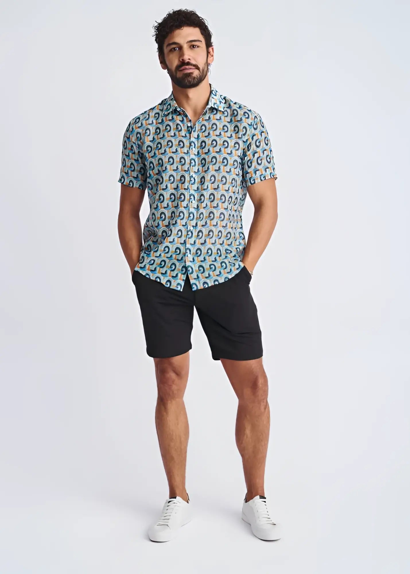 A man wearing a swirls lightweight cotton silk short sleeve shirt with blue teal and beige circular pattern