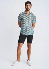 A man wearing a swirls lightweight cotton silk short sleeve shirt with blue green and yellow circular pattern