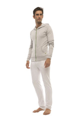 A man wearing white tactical urban dress pant yoga pants with a light gray zip-up hoodie with green zipper accents