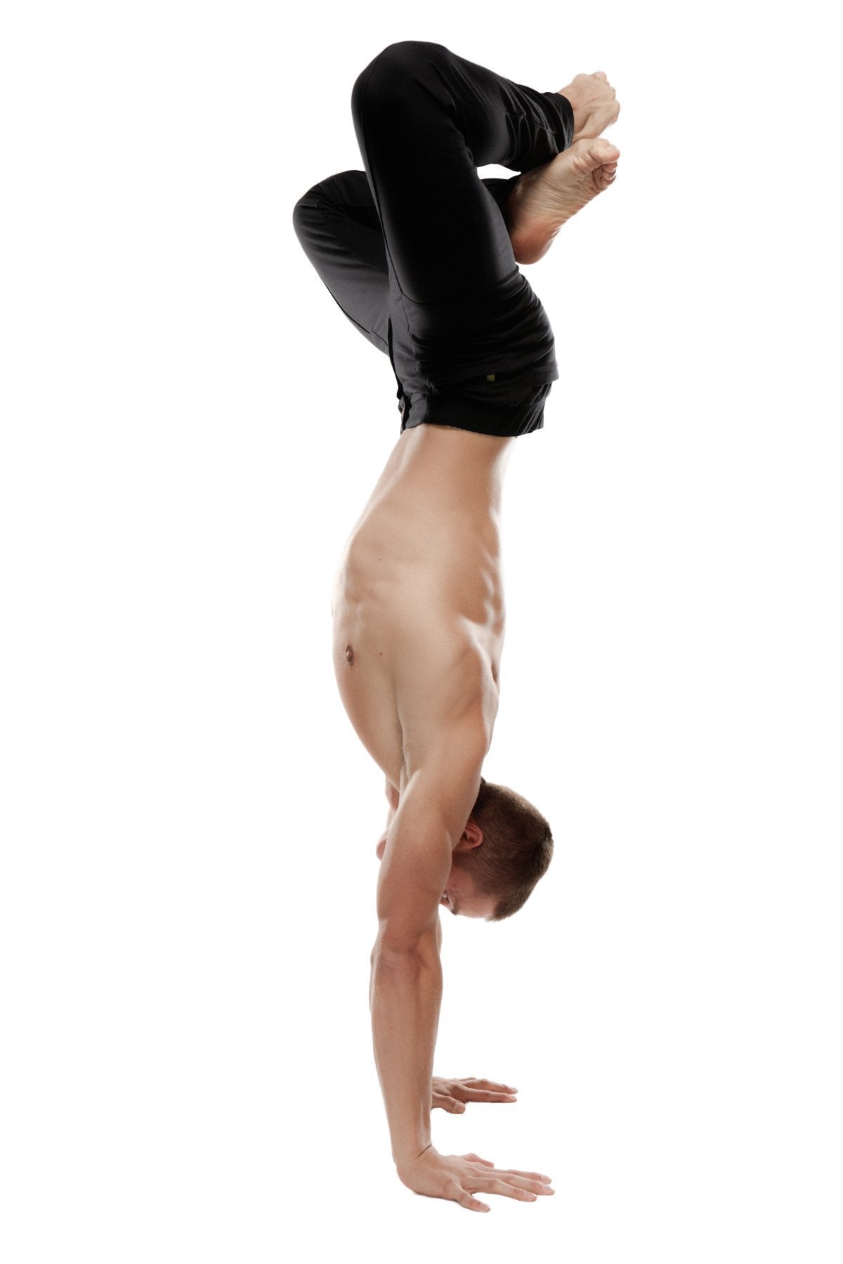 A shirtless man performing a handstand wearing black tactical urban at home dress pant yoga pants with bent legs