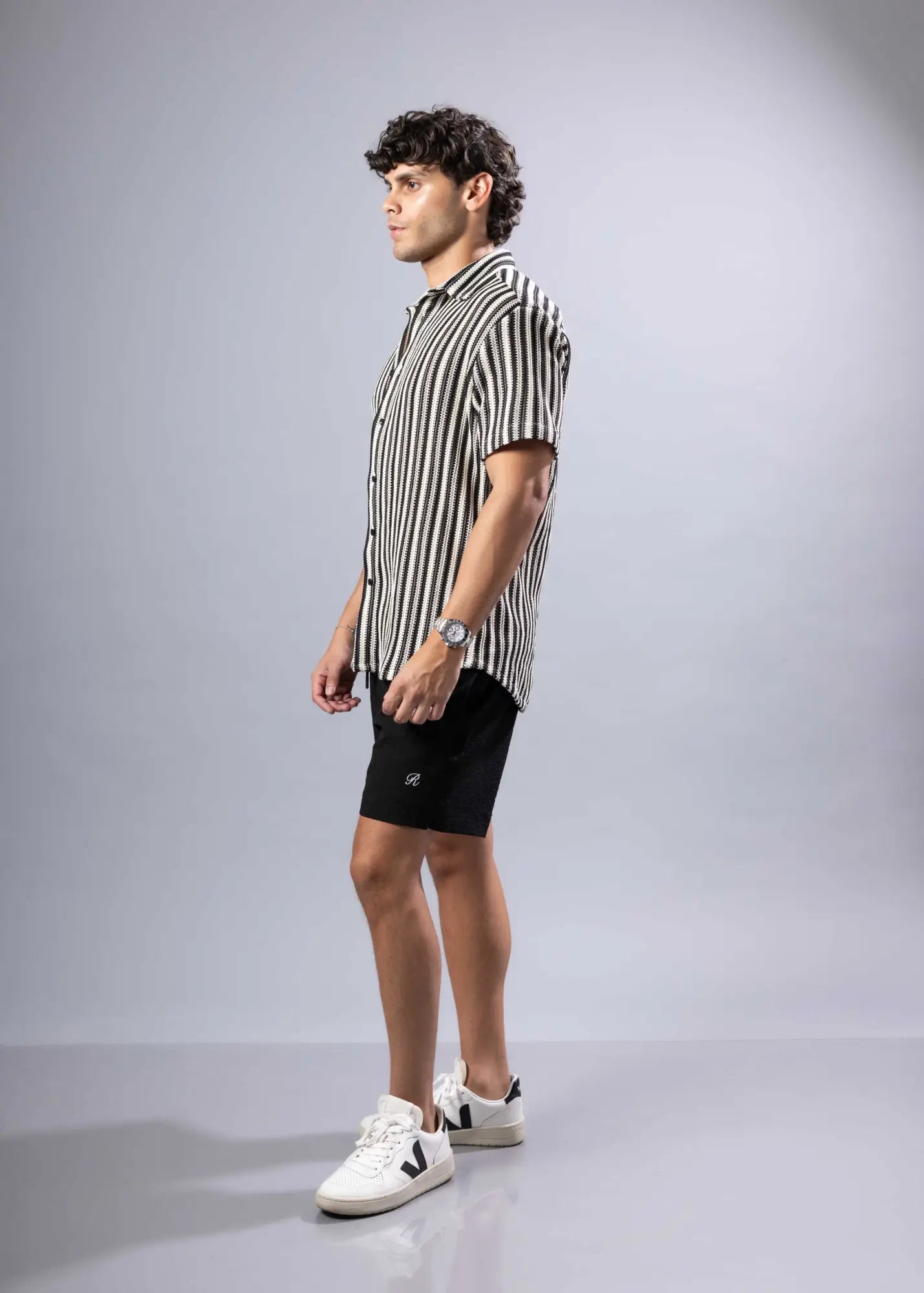 A man wearing a black and white vertically striped texture knit short-sleeved shirt perfect for casual wear