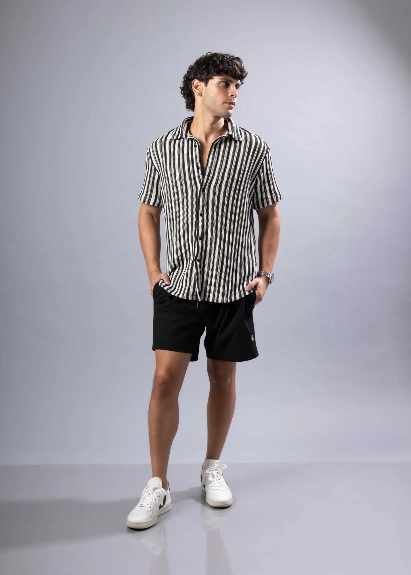 A man wearing a black and white vertically striped texture knit short-sleeved button-up shirt