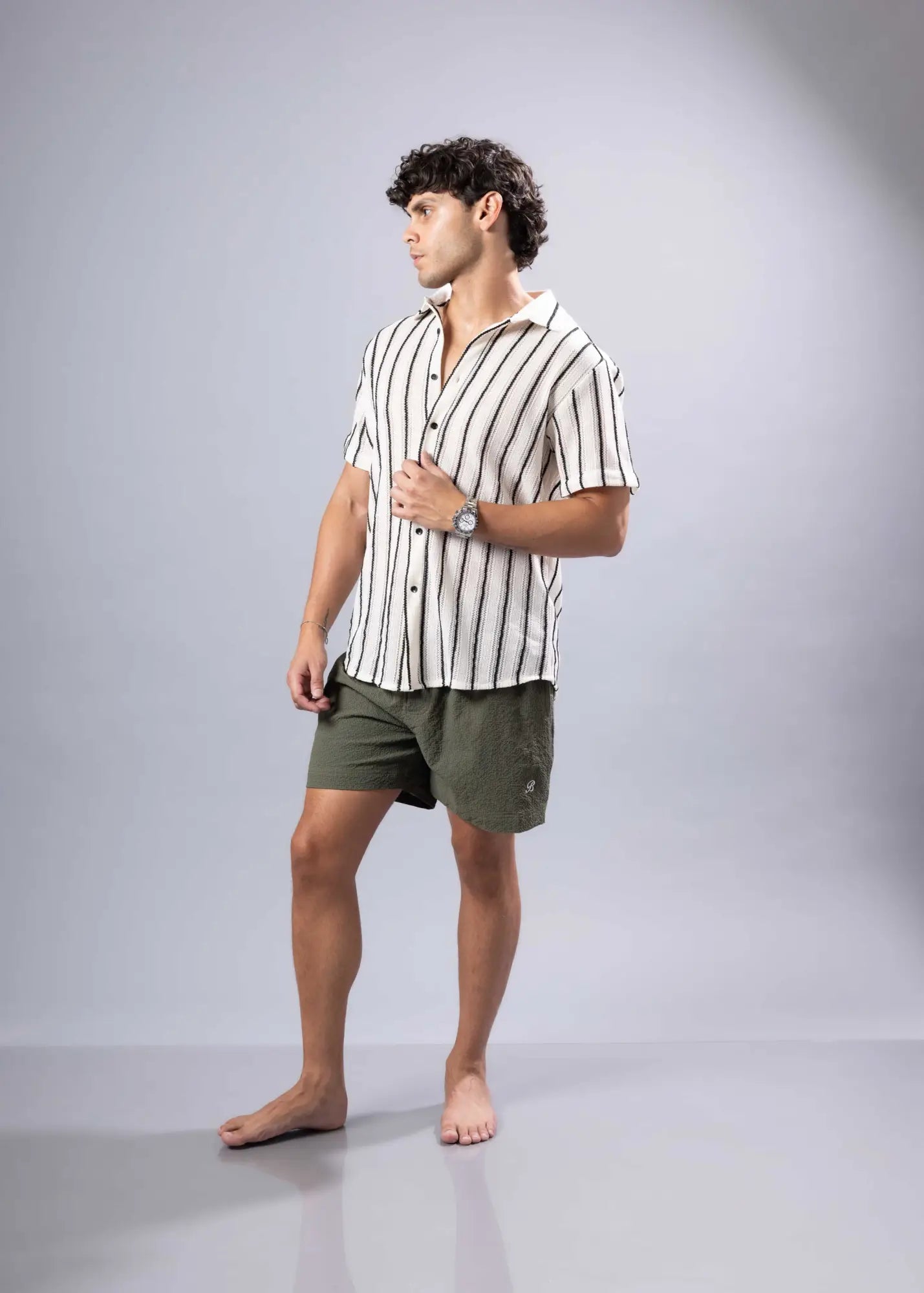 A man wearing a black and white vertical striped texture knit short-sleeved button-up shirt
